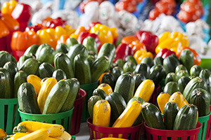 Photo of summer squash in baskets and fresh bell peppers at at farm market.